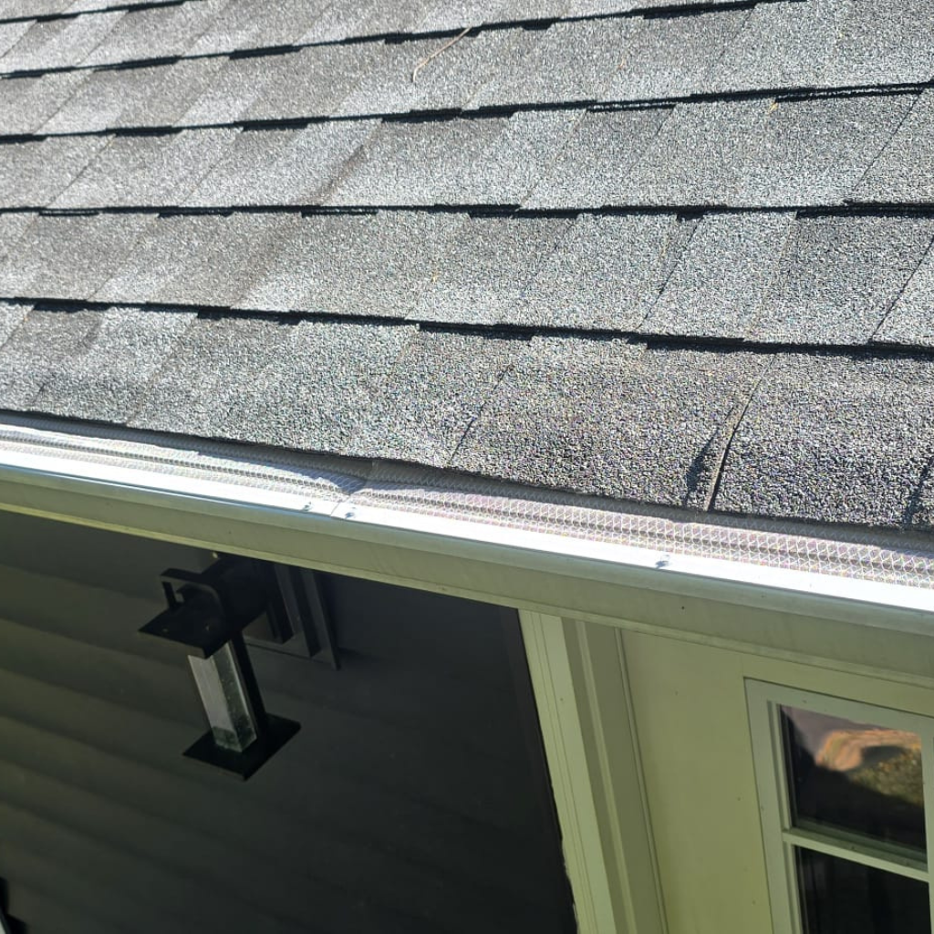gutter guard installed on the gutters of a home with black shingles on roof