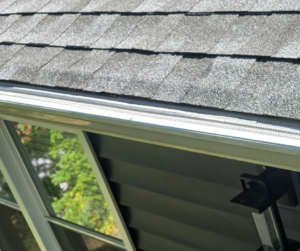 gutter guard installed on the gutters of a home with black shingles on roof